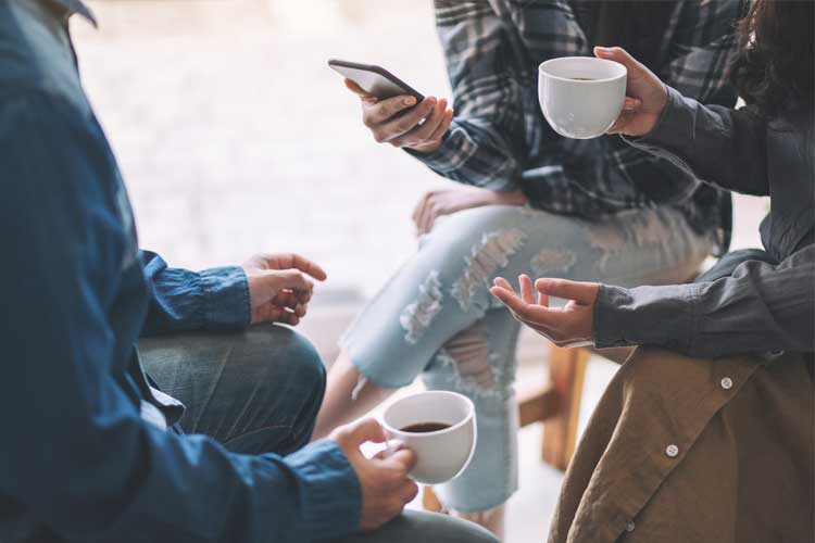 People talking in a group with coffee cups and phones